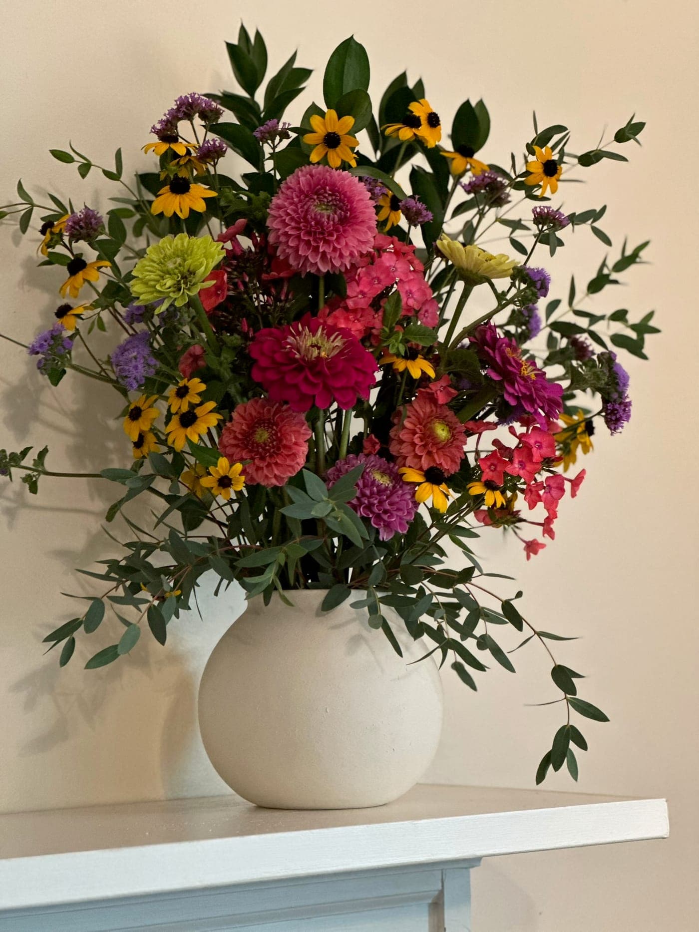 A bright seasonal bouquet arranged in a white ceramic vase